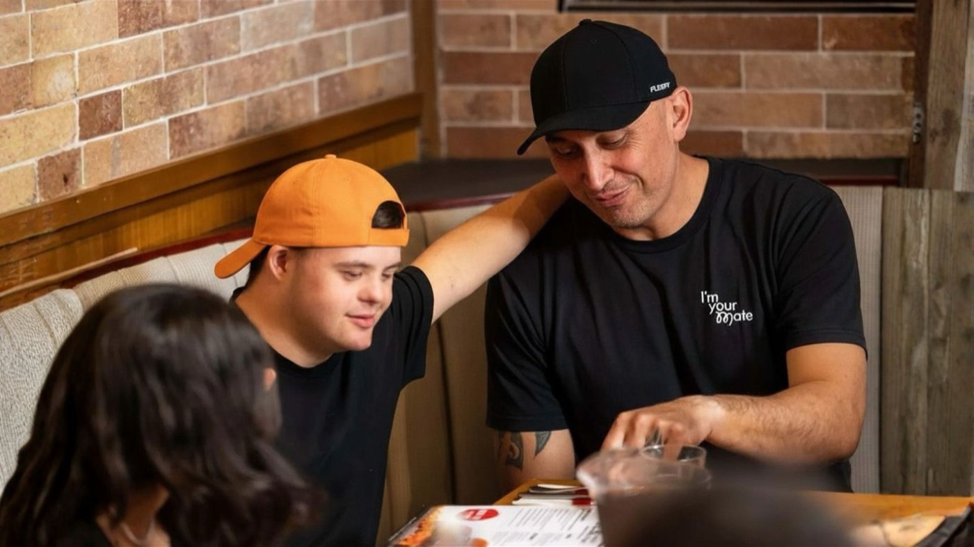 A support worker and a young participant sharing lunch together