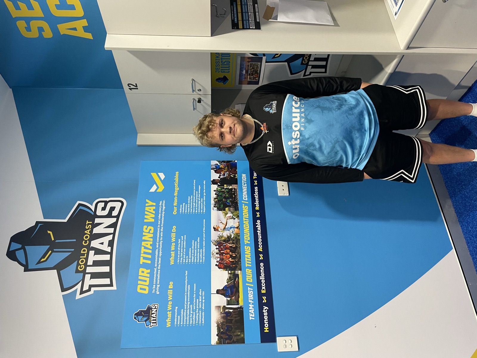 Hayden standing beside the Gold Coast Titans Way values wall in the team's facility